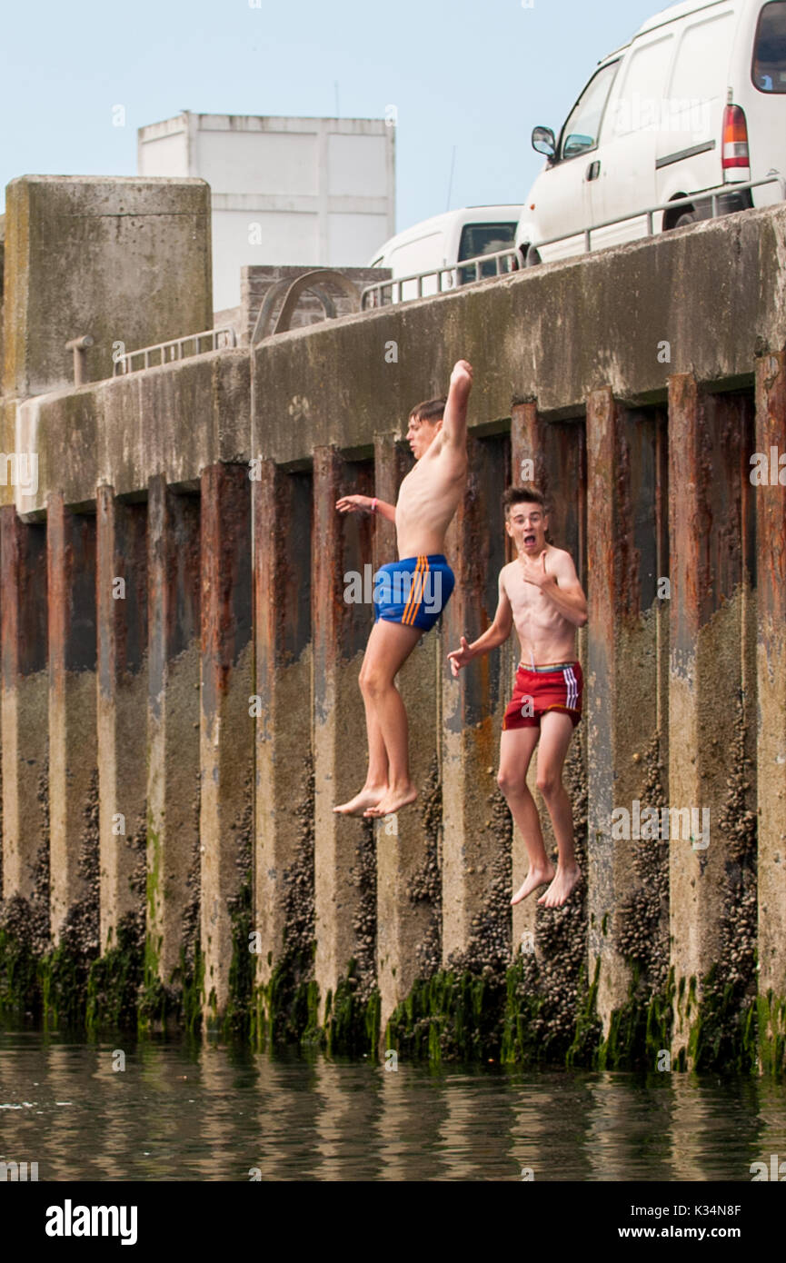 Two teenage boys jump off the pier into the sea in Schull, West Cork, Ireland. Stock Photo