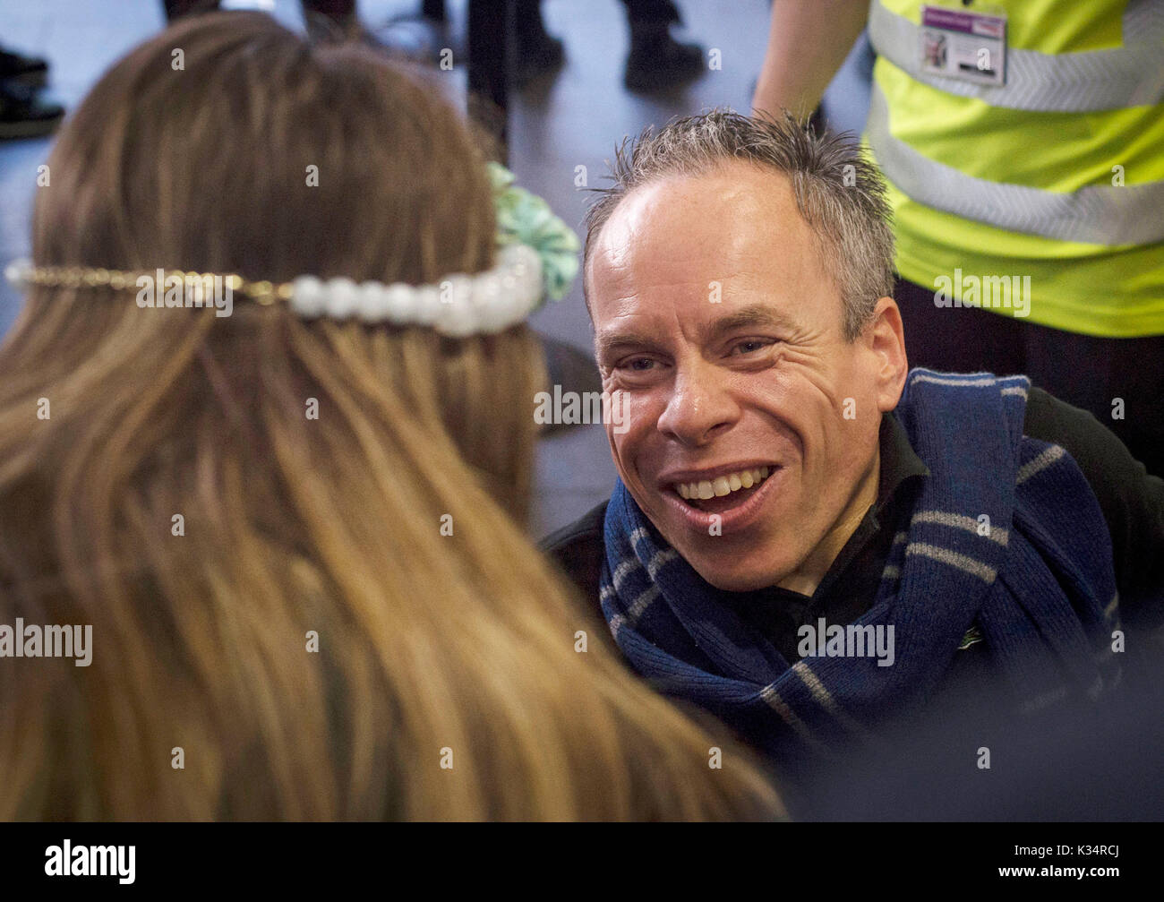 Warwick Davis, who played Professor Flitwick in the Harry Potter films, speaks to a fan at Platform 9 and 3/4 in King's Cross Station, London. Today is the day that Albus Severus Potter boarded the Hogwarts Express in the epilogue of Harry Potter And The Deathly Hallows. Stock Photo