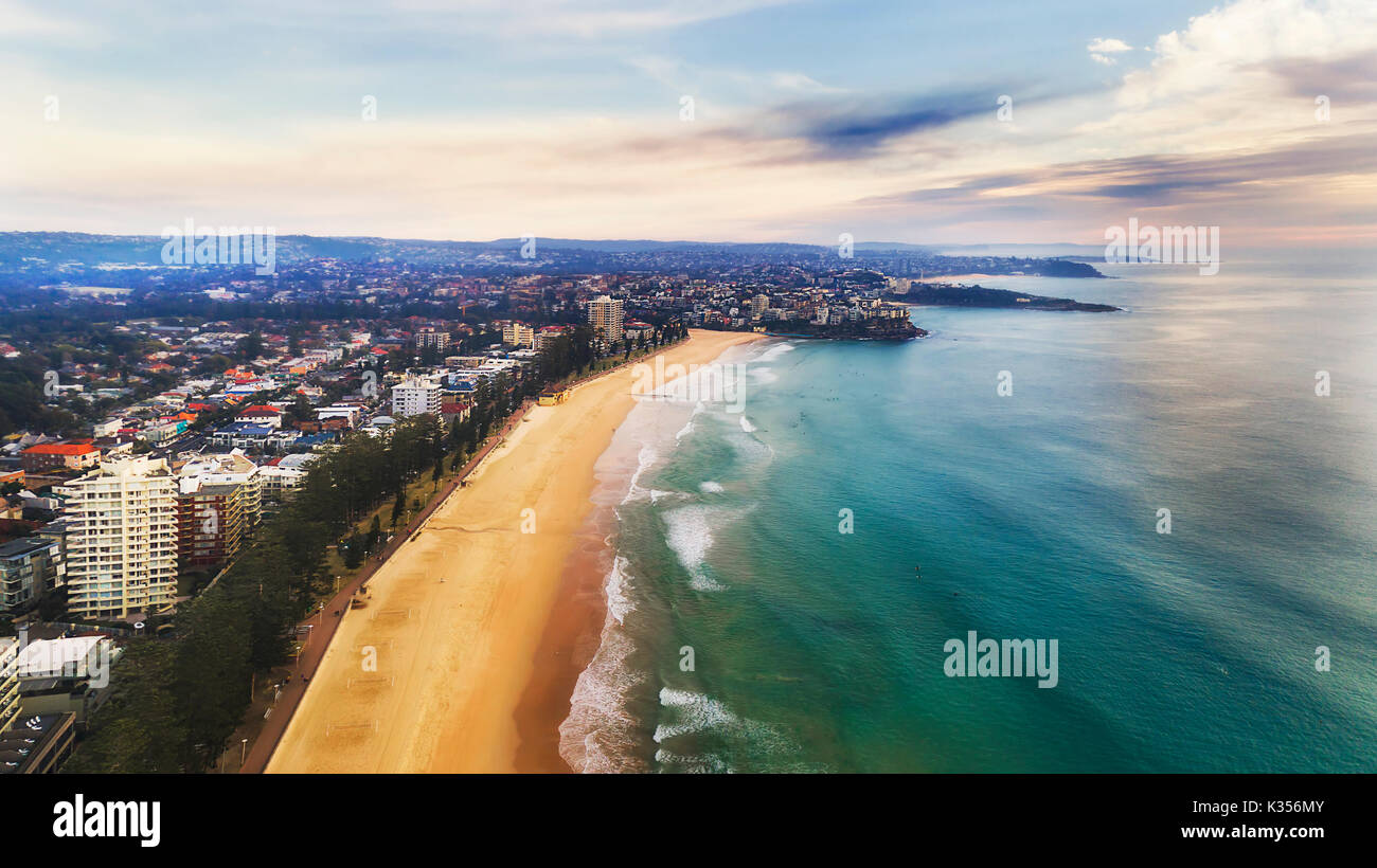 Manly beach and suburb waterfront facing surfing waves of Pacific ocean in morning from above - aerial elevated view. Stock Photo