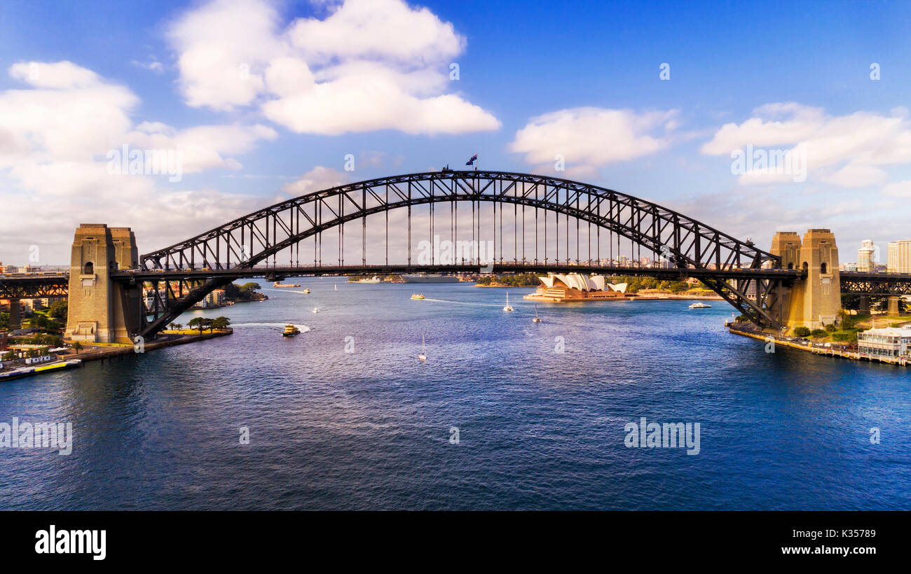 Elevated side view of the Sydney Harbour bridge connecting shores of Sydney harbour on a sunny day from above water. Stock Photo