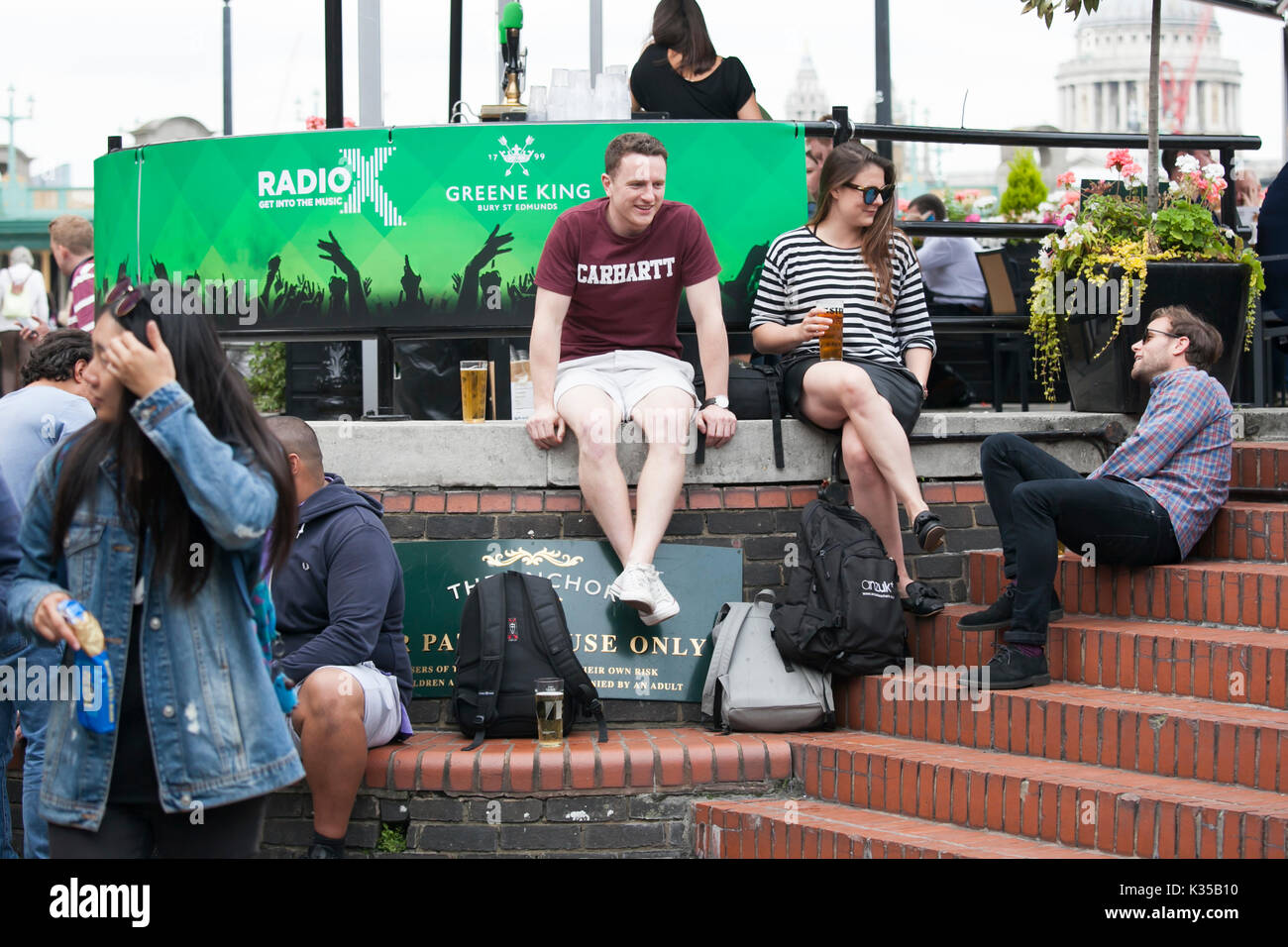 LONDON, ENGLAND - August 11 2017 A motley crowd sits outside the pub, drinks beer, talks with friends. Southbank Stock Photo