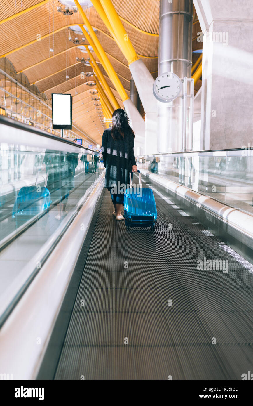 Woman in an Airport walking fast in a Moving Walkway Stock Photo