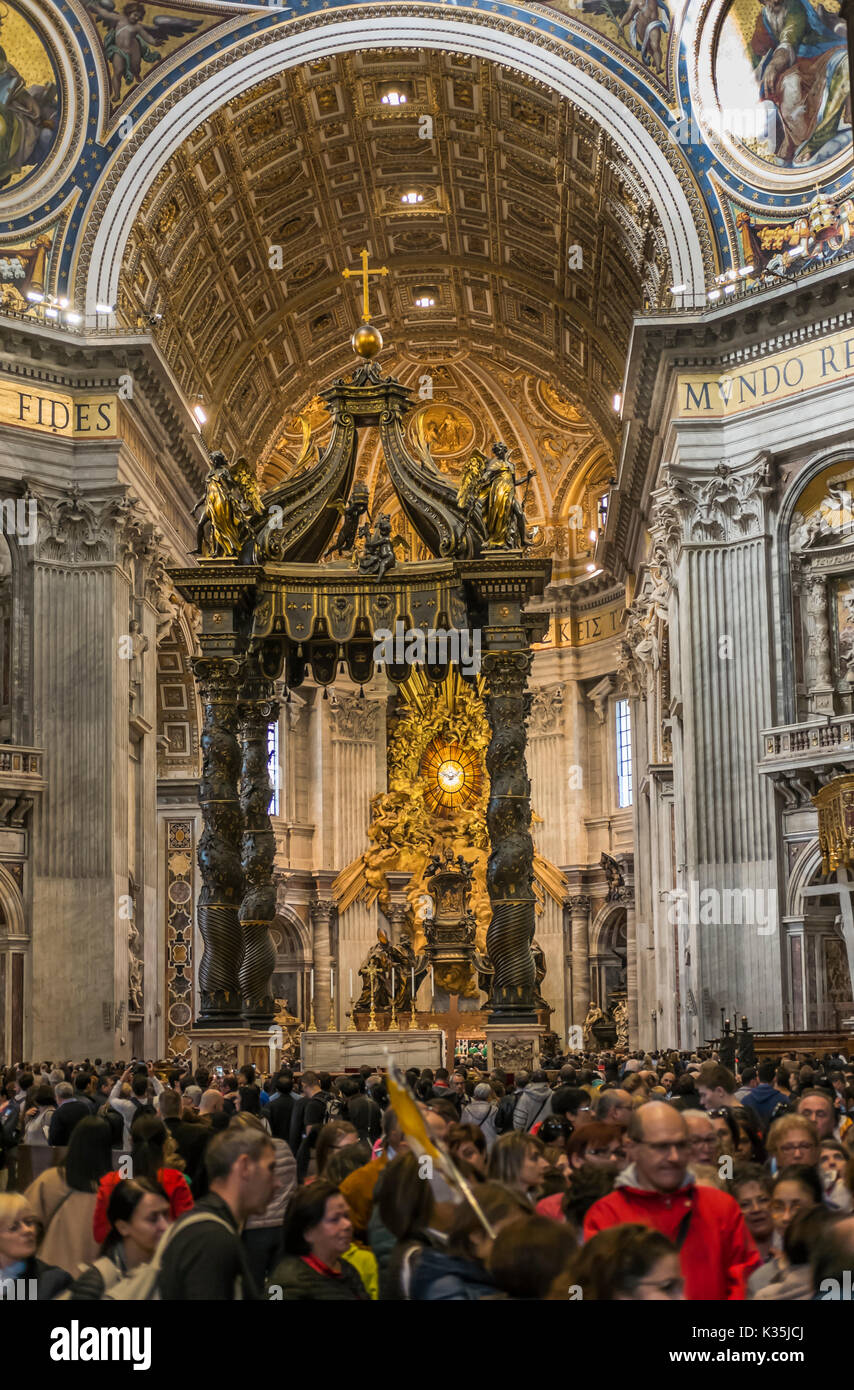 visitors inside st. peter´s basilica, altar with berninis baldacchino and cathedra petri and gloria in the background Stock Photo