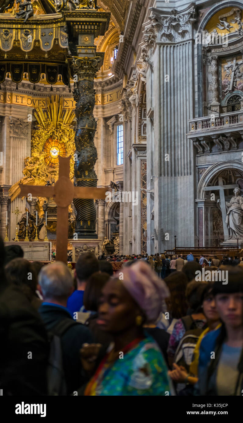 visitors inside st. peter´s basilica, altar with berninis baldacchino and cathedra petri and gloria in the background Stock Photo