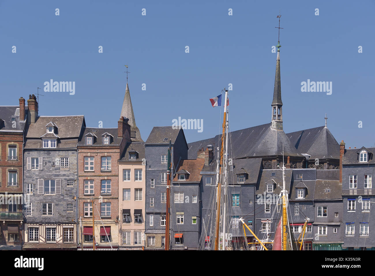 Facades of building and the Sainte-Catherine church with de boat mast at Honfleur, commune in the Calvados department in the lower Normandy region in Stock Photo