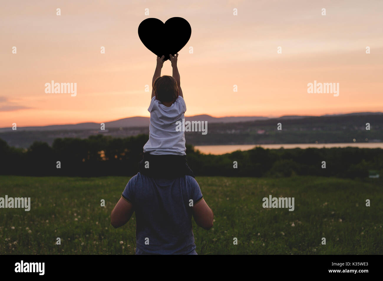 Young father walking with his young son in the meadow at the sunset Stock Photo