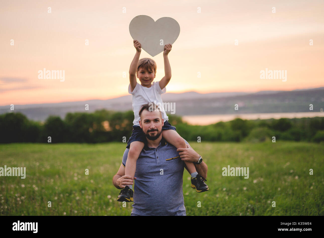 Young father walking with his young son in the meadow at the sunset Stock Photo