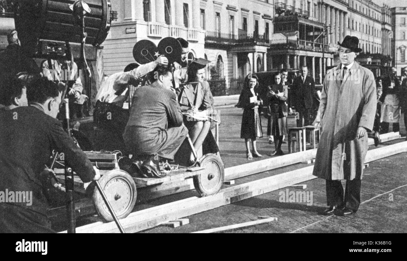 THE FALLEN IDOL  DIRECTED BY CAROL REED RALPH RICHARDSON TAKES CARE TO STAY ON THE LINE WHICH WILL ENSURE HE STAYS IN FOCUS DURING FILMING IN BELGRAVE SQUARE. THE DIRECTOR SQUATS ON THE CAMERA DOLLY   FR48.9/16 THE FALLEN IDOL  DIRECTED BY CAROL REED RALPH RICHARDSON TAKES CARE TO STAY ON THE LINE WHICH WILL ENSURE HE STAYS IN FOCUS DURING FILMING IN BELGRAVE SQ     Date: 1948 Stock Photo