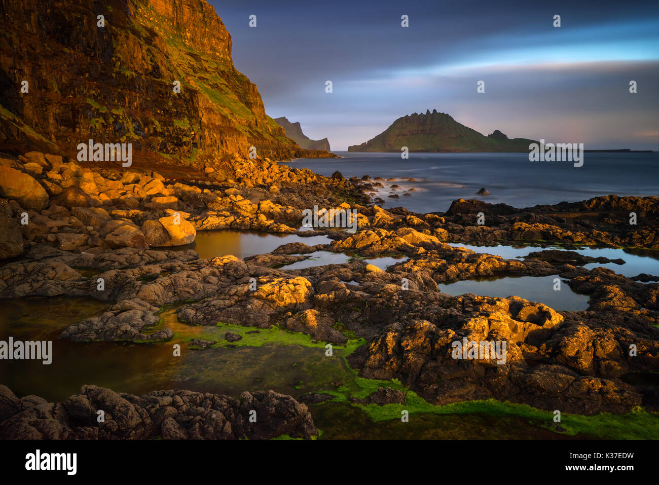 Gasadalur rocky harbour with Tindholmur island in sunset, Faroe Islands ...