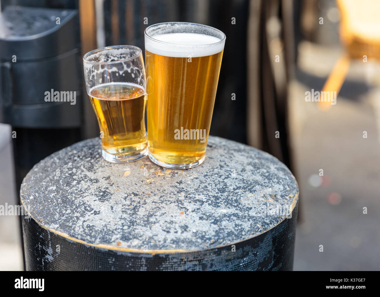 British pint and half pint of beer resting on a concrete stool, UK