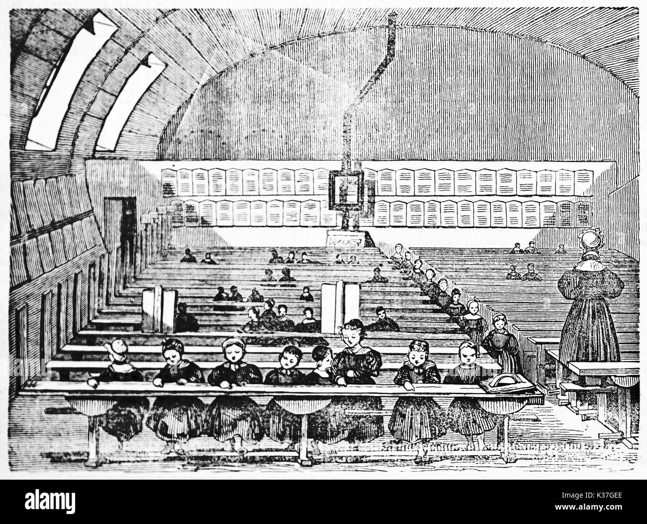 First ancient mutual primary school classroom in France. Large space with school children and teacher. Old Illustration by unidentified author published on Magasin Pittoresque Paris 1834. Stock Photo