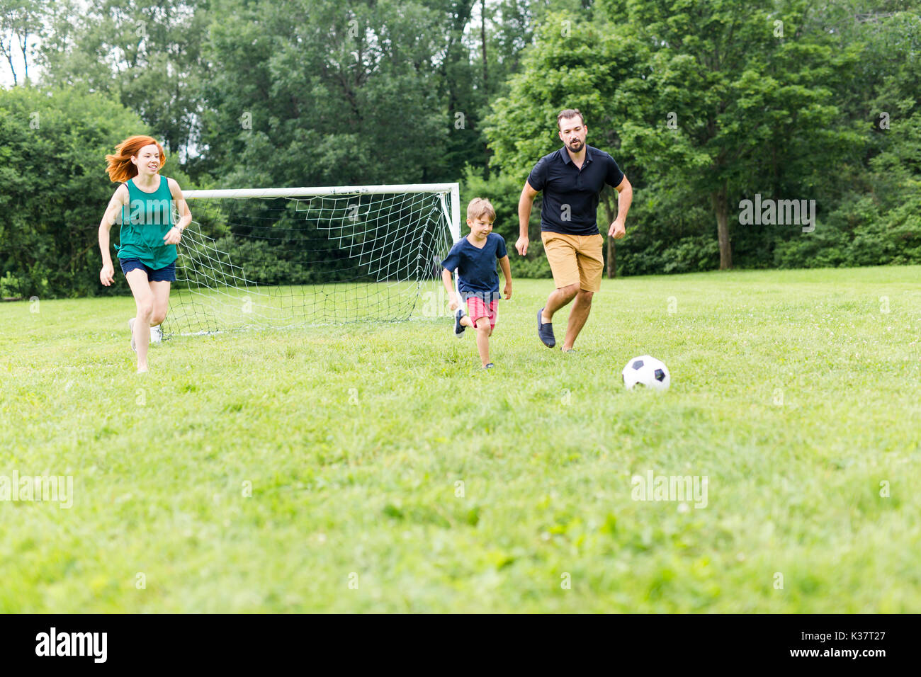 Cheerful family playing football in a park Stock Photo - Alamy