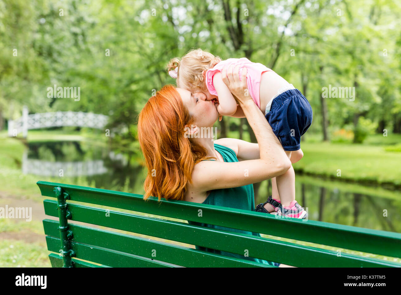 mother and her little daughter sitting on a park bench Stock Photo - Alamy
