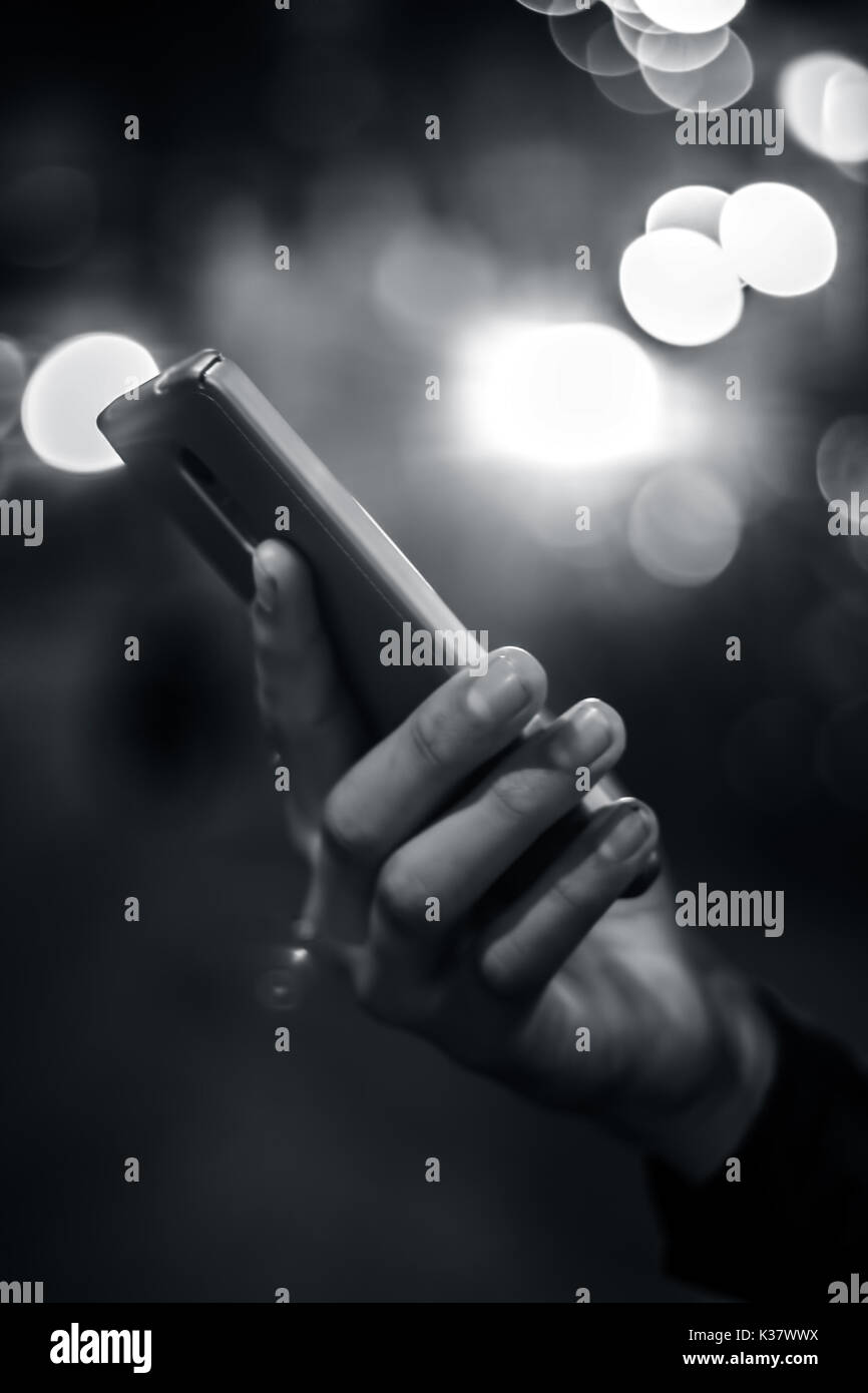 A hand holding and using digital smart phone at night. Stock Photo