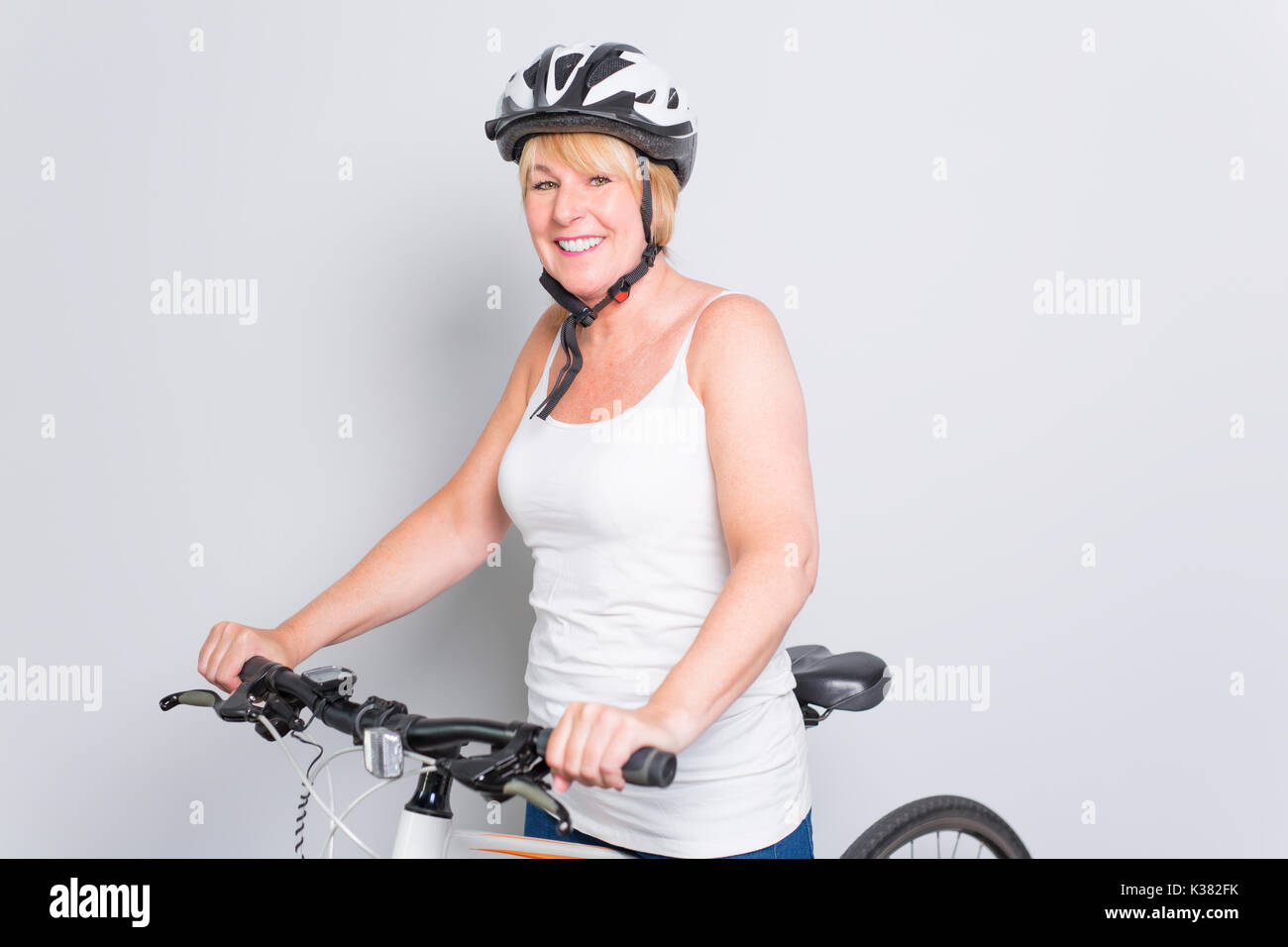 senior woman on the side of a bike in studio white background Stock Photo