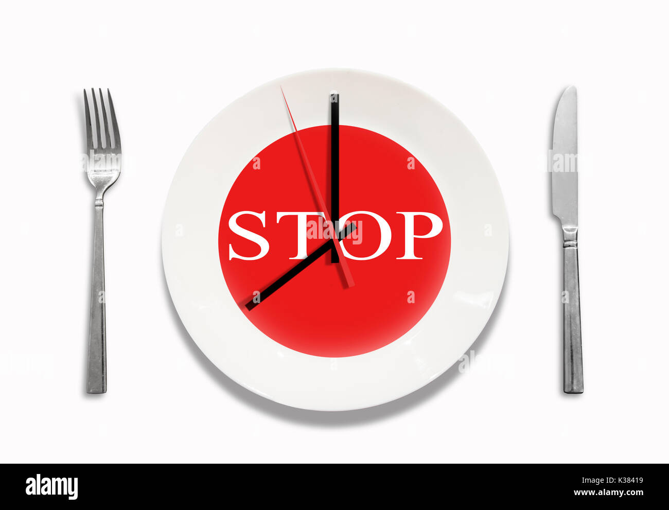 Conceptual idea. white plate with clock in the interior. Knife and fork. On the background of the plate the sign is STOP. after 8 pm. Stock Photo