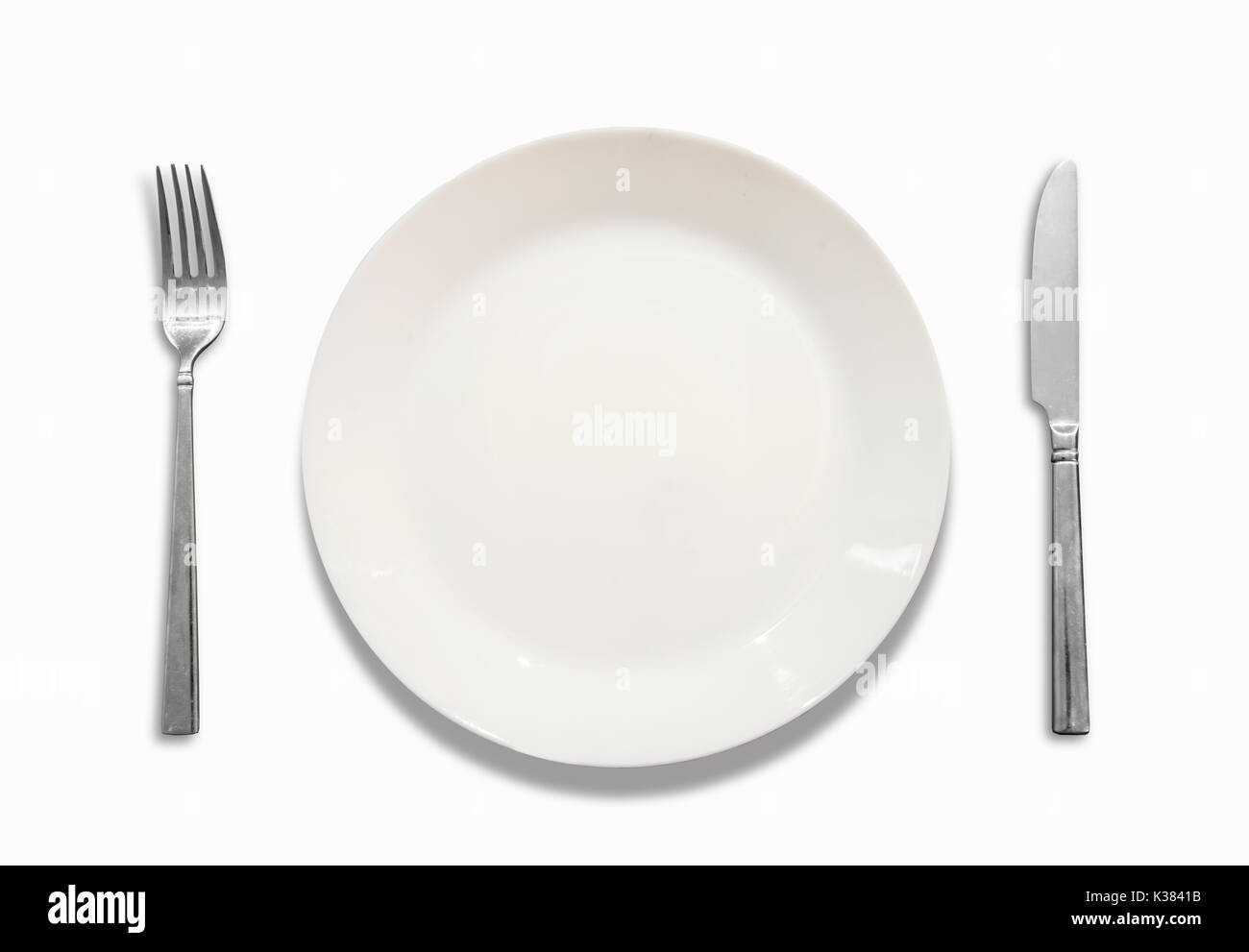 White plate, knife, fork, on white background. Stock Photo