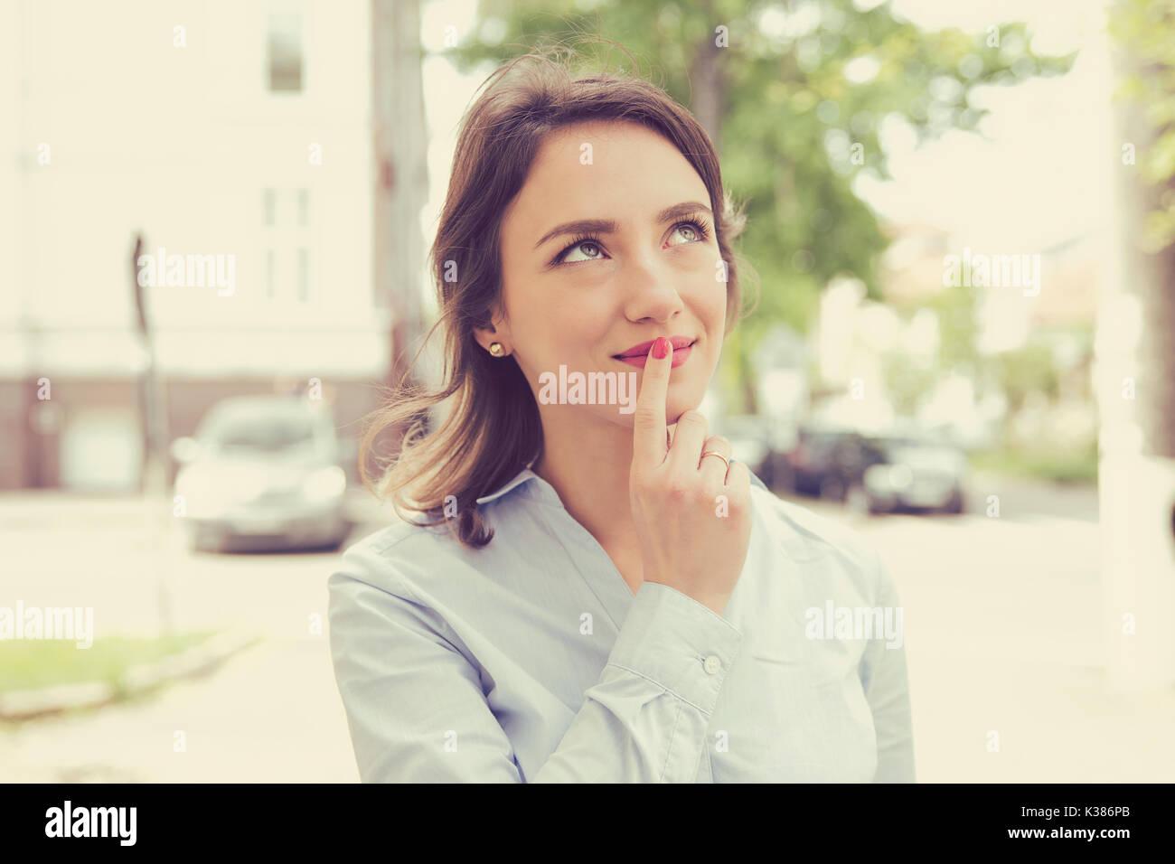 Woman thinking and looking sideways standing on a city street Stock Photo