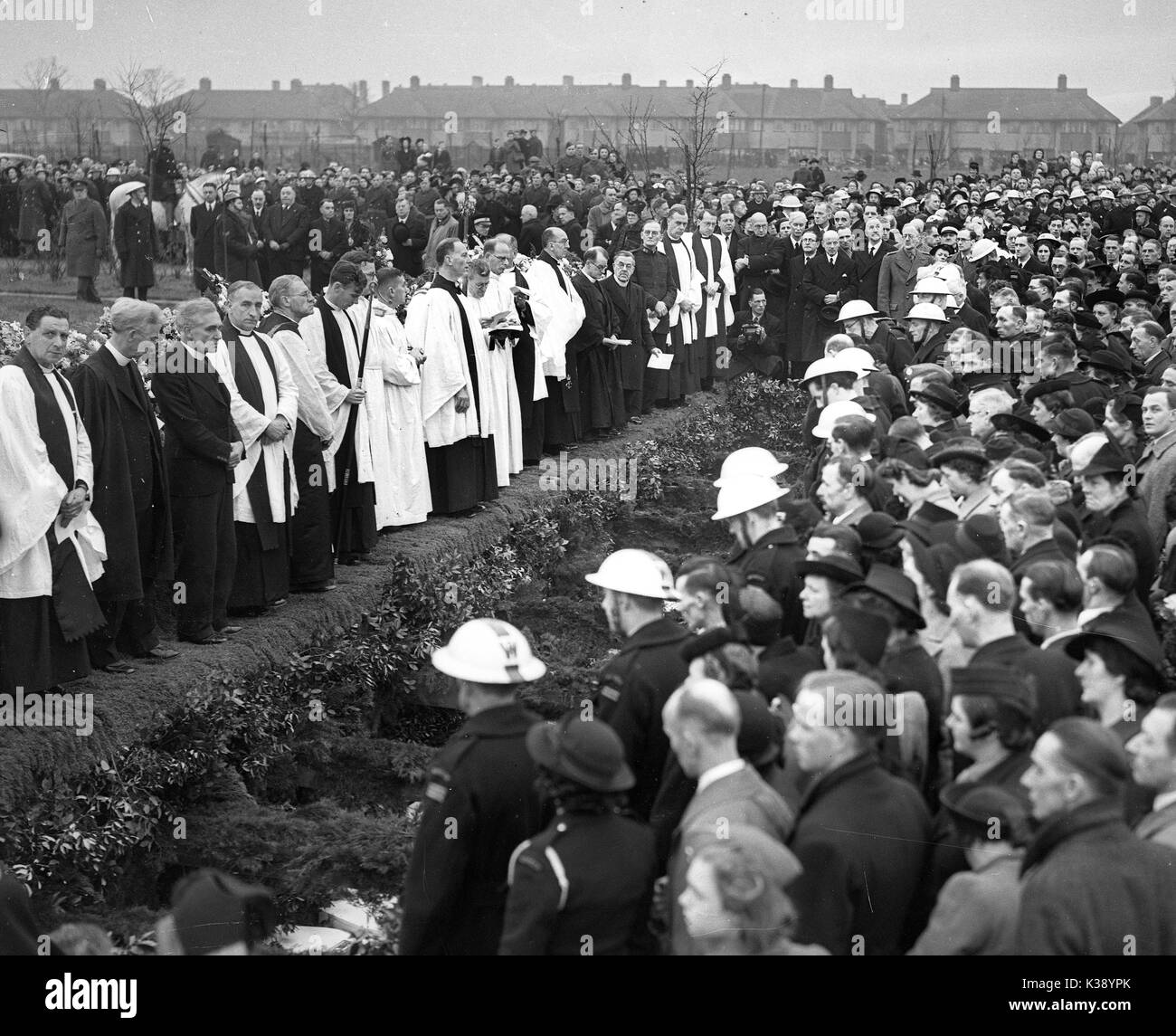 Mourners surround the mass grave as the 44 victims of a German bombing raid are buried at Hither Green Cemetery in London, World War II, 27th January 1943. Thirty-eight children and six teachers were killed when Sandhurst Road School in Catford, south London took a direct hit when a Fokker-Wolf FW 190A-4  dropped a 1,100lb bomb at 12.30pm on Wednesday, 20 January 1943. Stock Photo