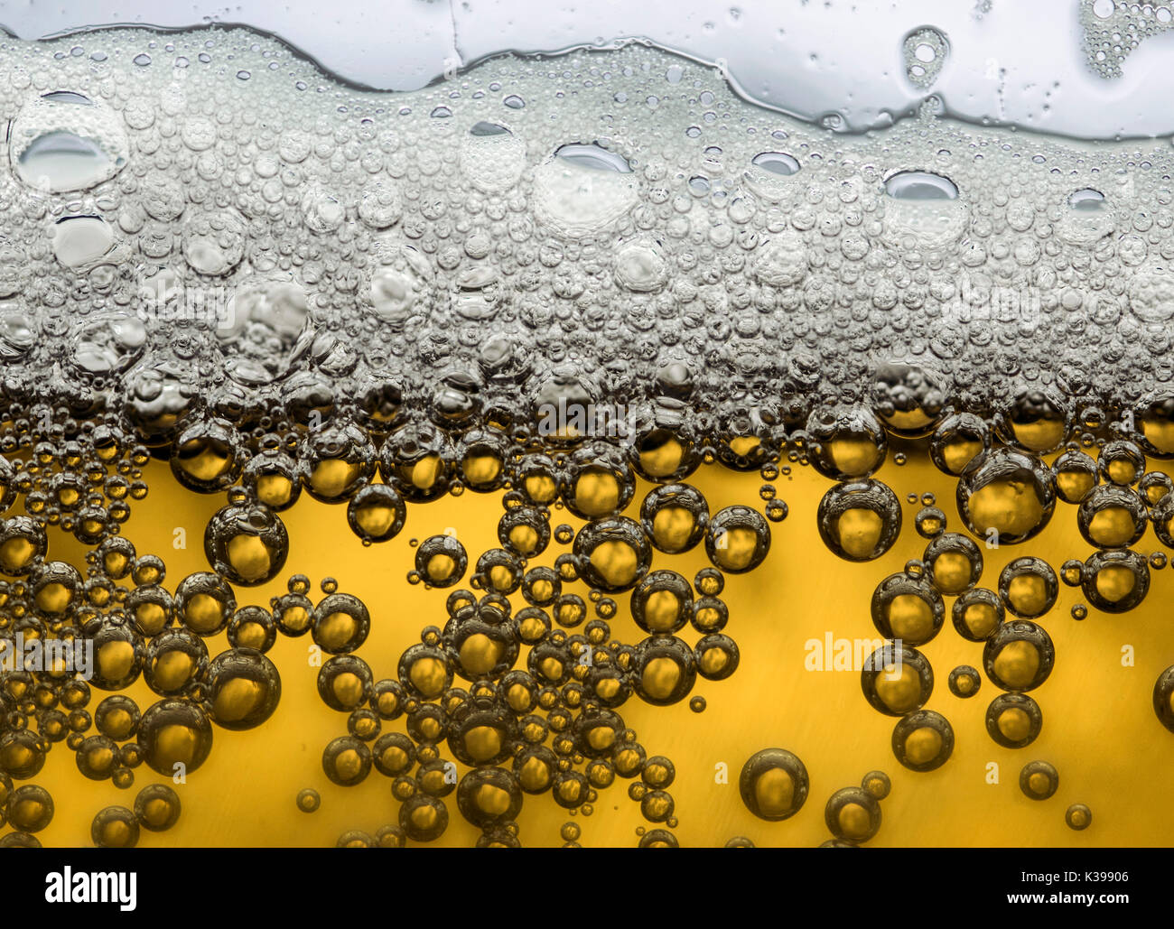 Yellow cold beer bubbles and foam closeup macro, backlit Stock Photo