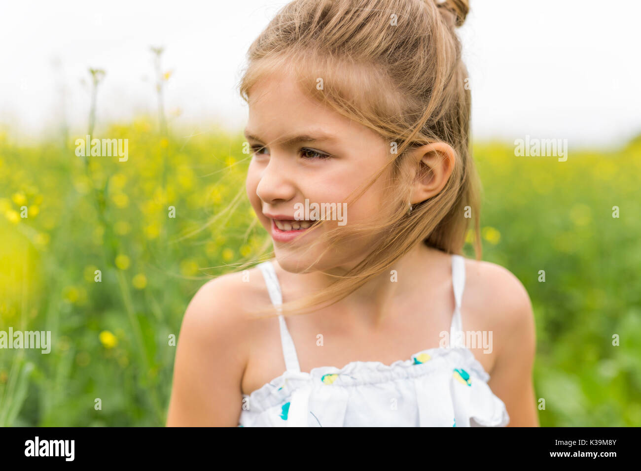 Happy girl in a field of yellow flowers Stock Photo - Alamy