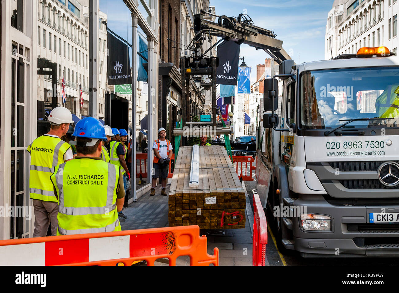 Construction Workers Take Delivery Of A Consignment Of Wood, Old Bond Street, London, UK Stock Photo