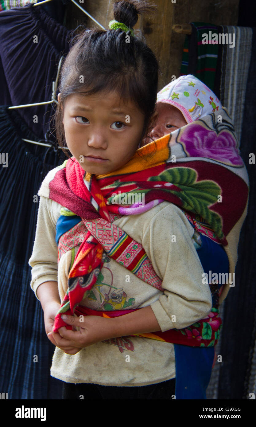Vietnamese child carries little brother on her back, while looking plaintive, but never begging on Oct 21, 2011 Stock Photo