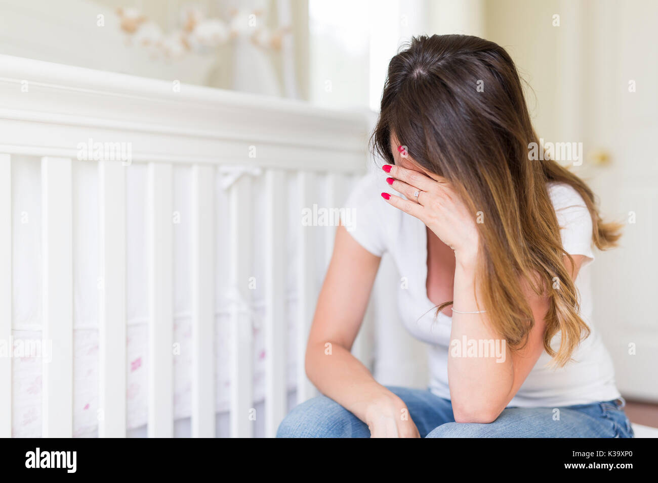 Depressed young woman in baby room Stock Photo