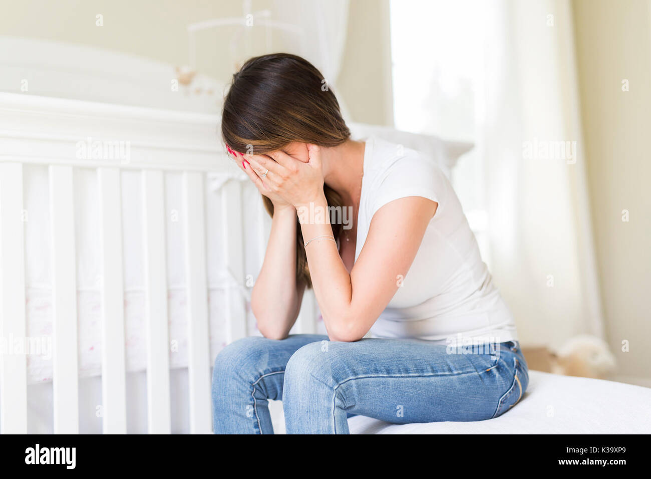 Depressed young woman in baby room Stock Photo
