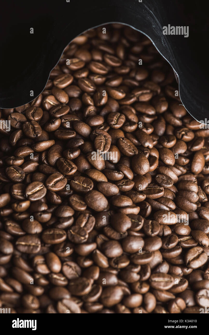 Fresh roasted coffee bean coming out of package. Stock Photo