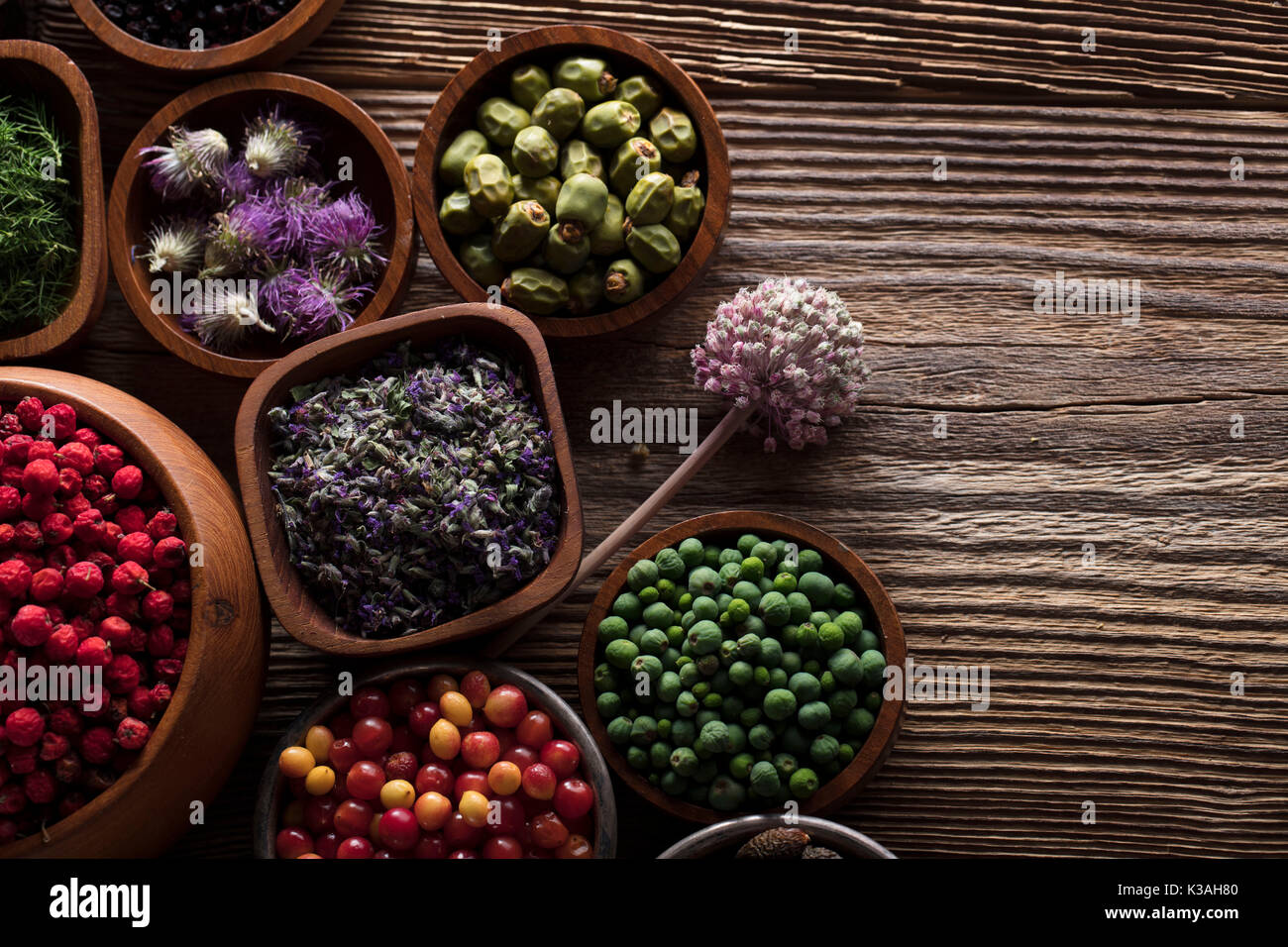 Natural medicine.  Herbs, berries and flowers in bowls on wooden table. Stock Photo