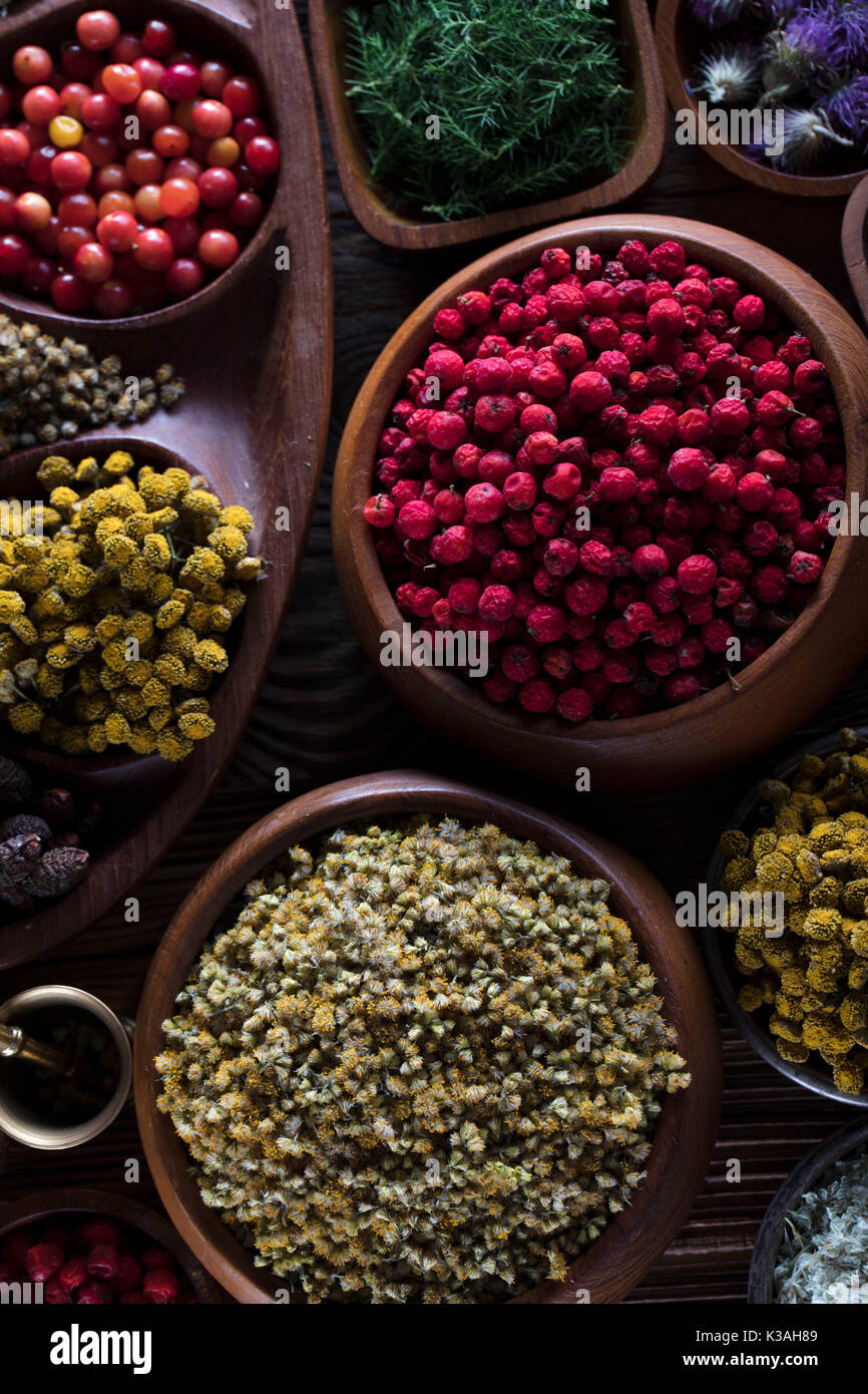 Natural medicine.  Herbs, berries and flowers in bowls on wooden table. Stock Photo
