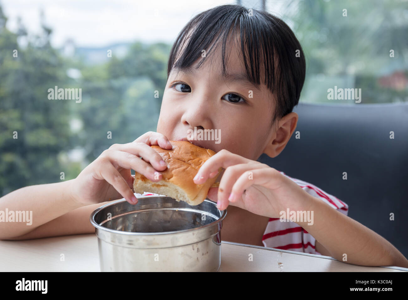 Asian Chinese little girl eating bread at indoor restaurant Stock Photo