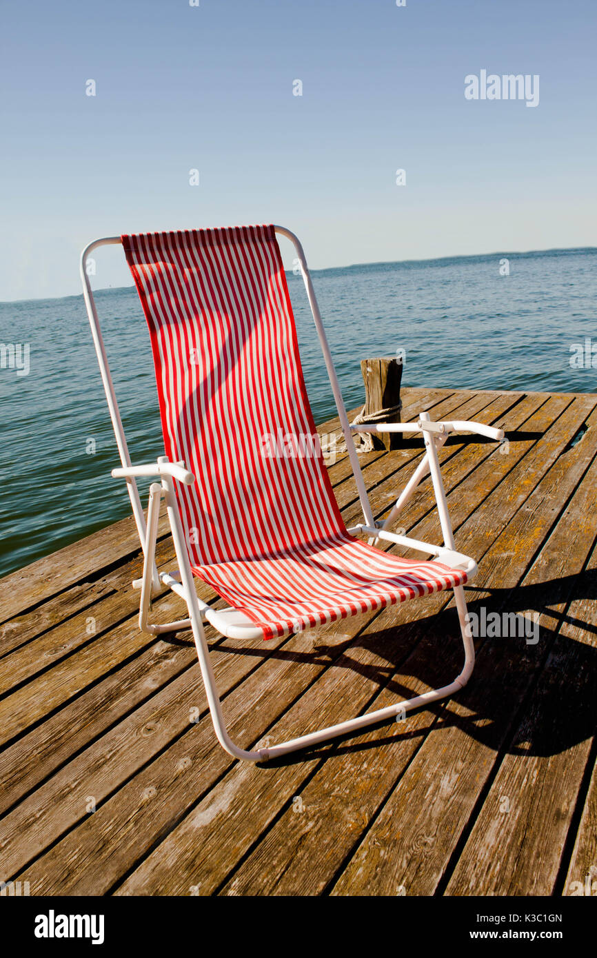 red and white striped vintage beach chair on the lake pier in sweden Stock Photo