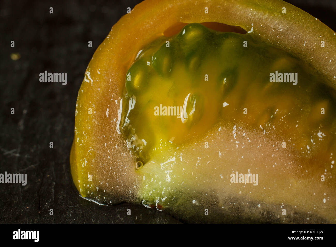 tomato slice with seeds isolated close up in black board Stock Photo