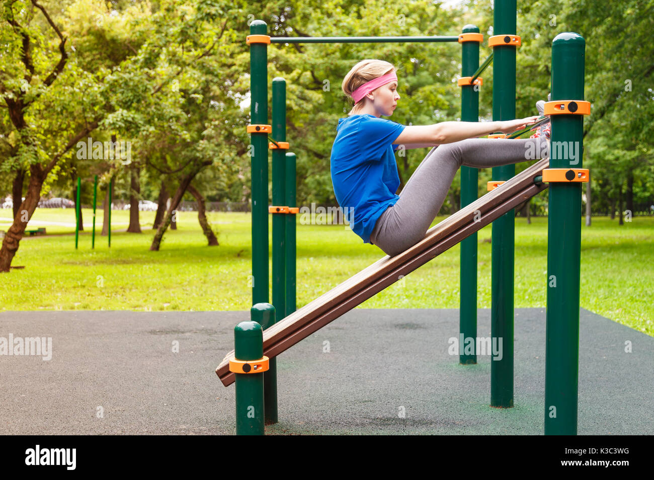 young beautiful girl swings the press in the gym outdoor sport place Stock Photo