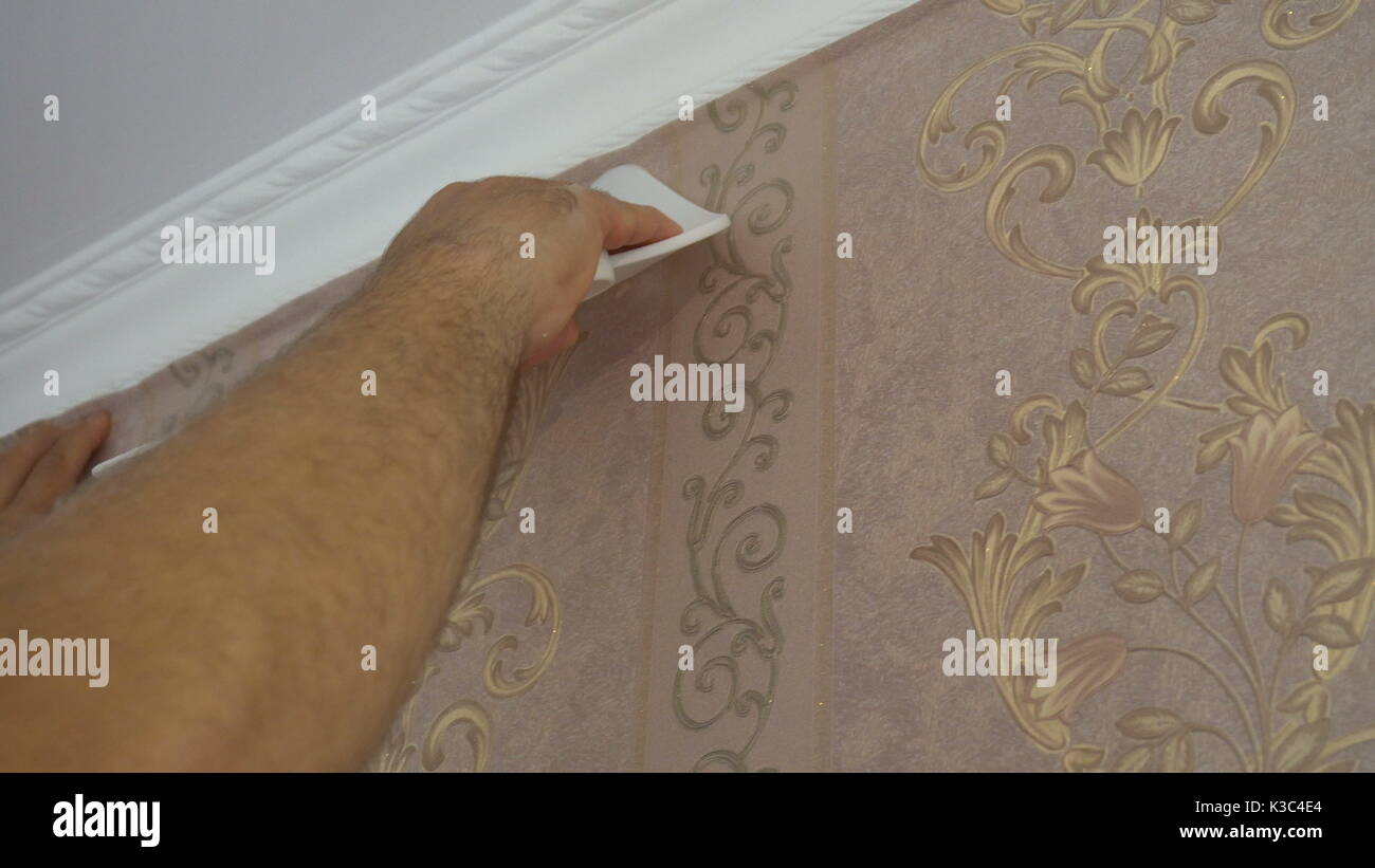 the process of gluing Wallpaper on the wall,the hand of the worker to