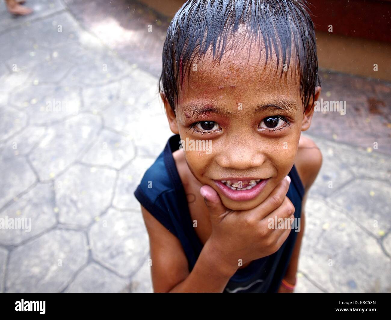 MARIKINA CITY, PHILIPPINES - AUGUST 28, 2017: A young boy smiles for the camera after getting himself wet at a water fountain at an outdoor park. Stock Photo