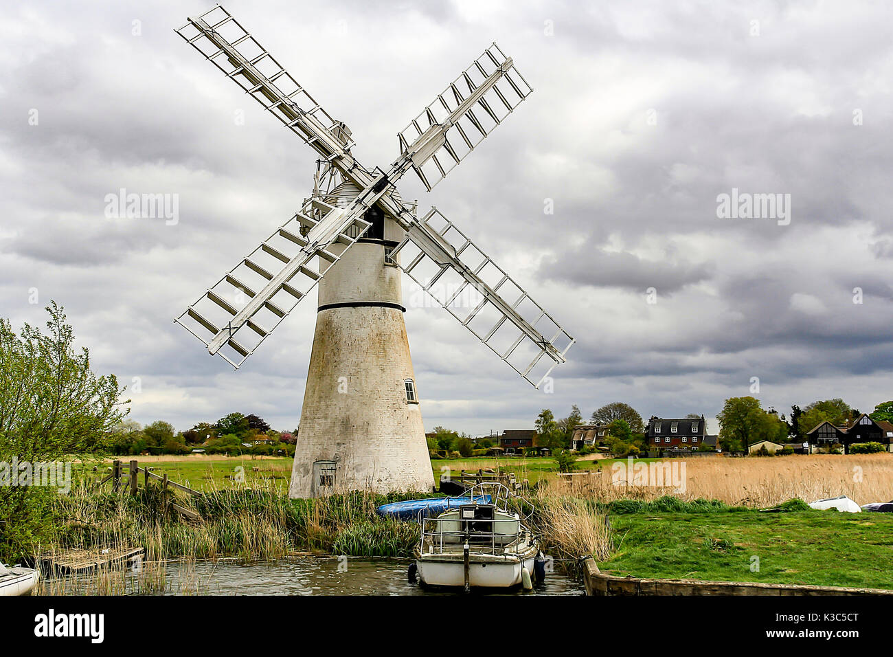 Windmill on the Norfolk Broads with a small boat moored alongside.  The image was taken on the 11 May 2013mill, power, turbine, generator, renewable, Stock Photo
