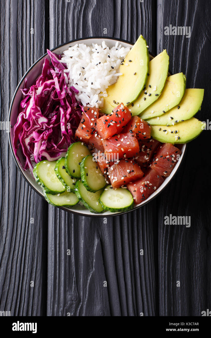 Raw Organic Ahi Tuna Poke Bowl with Rice and Veggies close-up on the table. Top view from above vertical Stock Photo