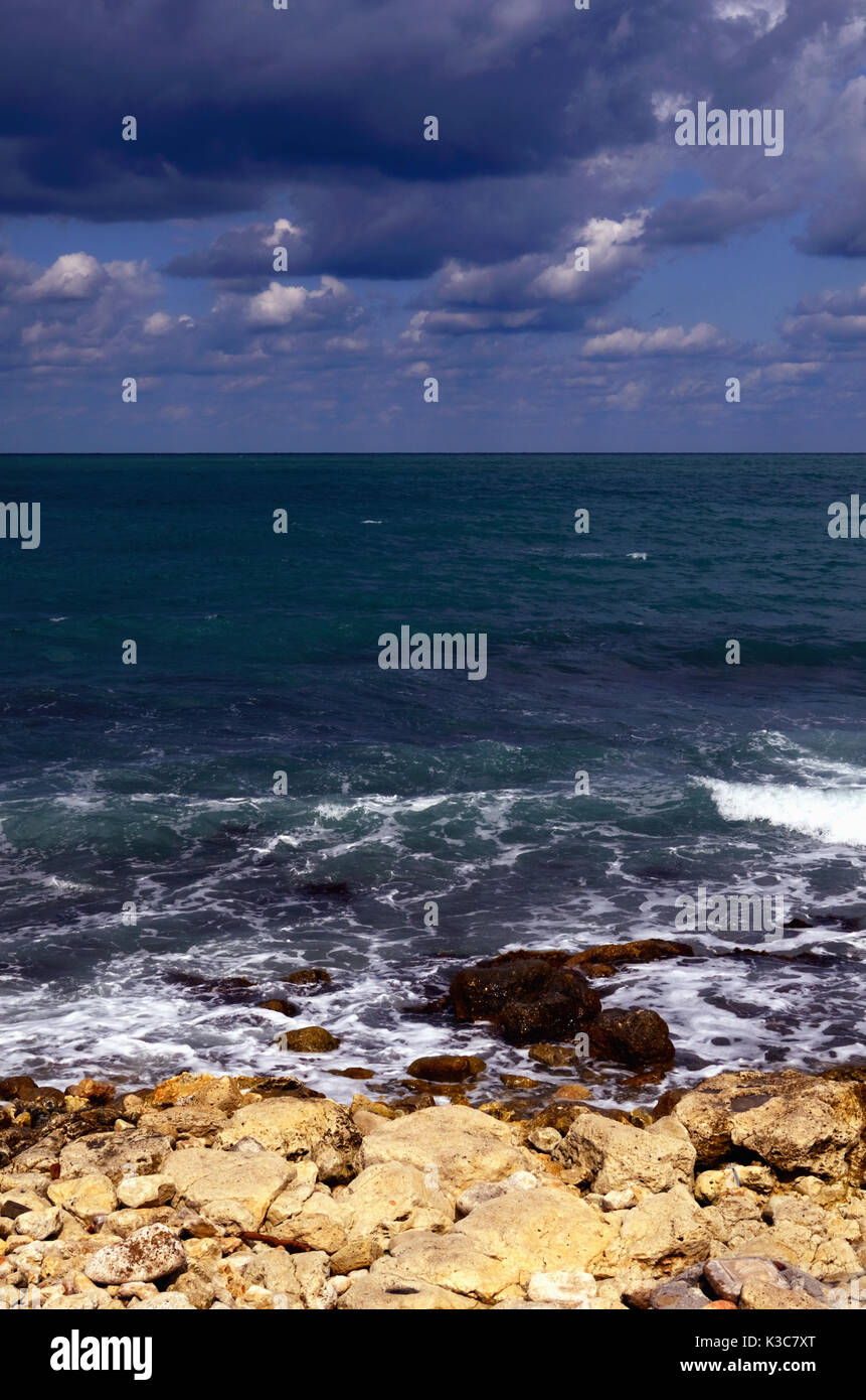 Sea with Breaking Waves seen from a Stony Shore; Clouds in the Sky. Photo taken at Black Sea in Summer. Stock Photo