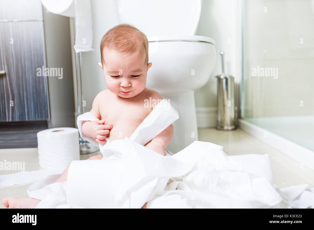 Toddler ripping up toilet paper in bathroom Stock Photo Alamy