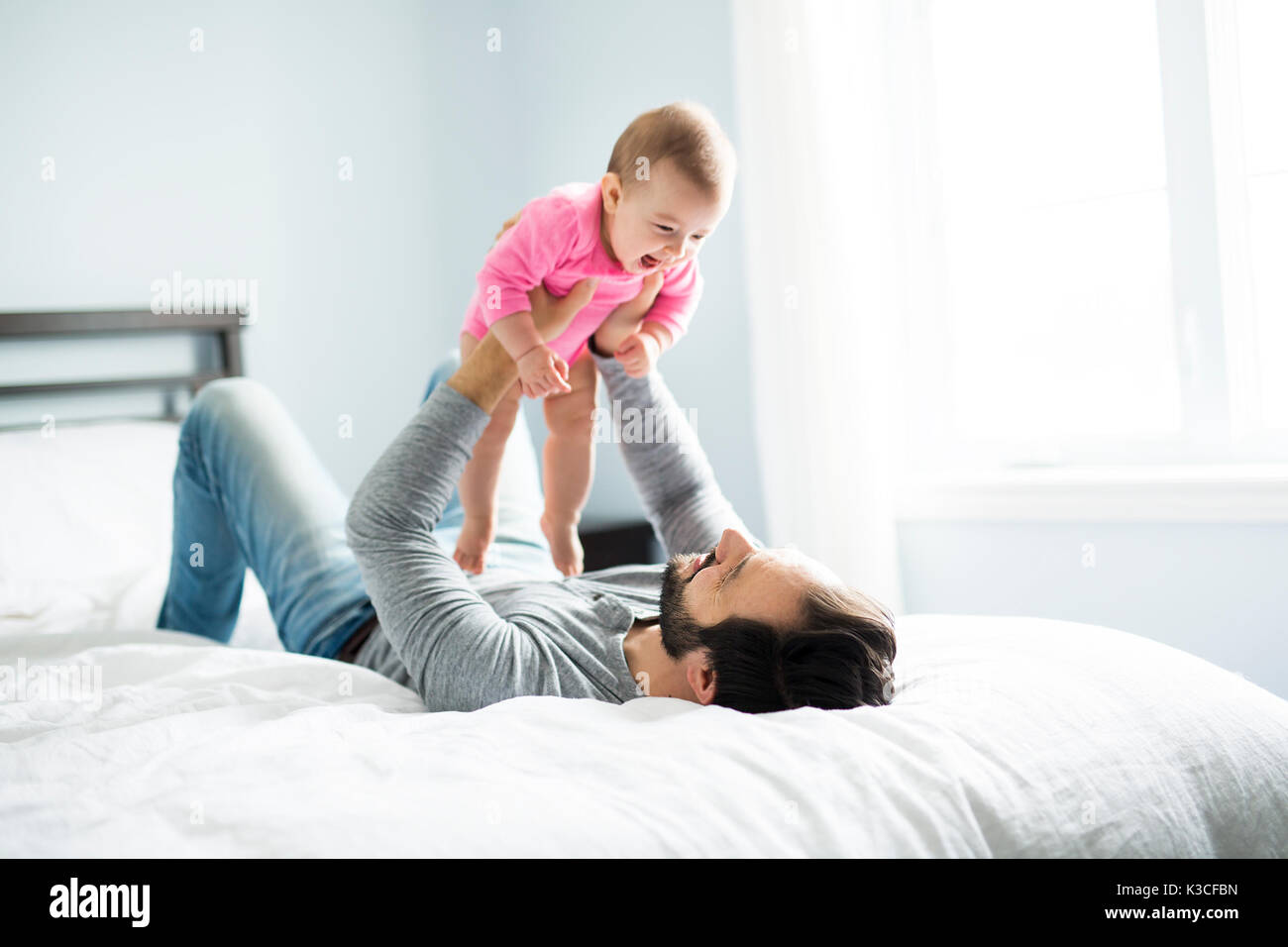 happy father playing with adorable baby in bedroom Stock Photo