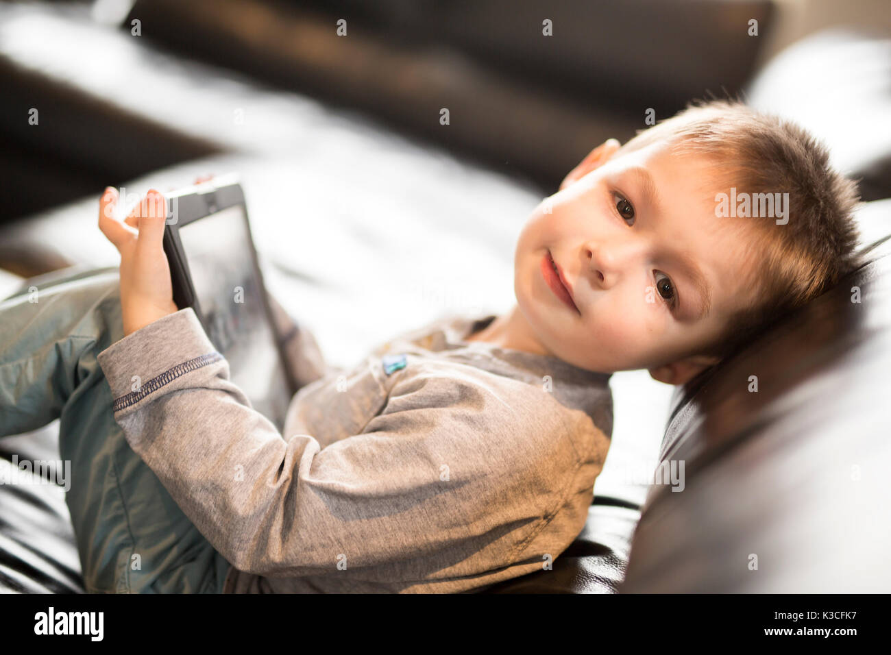 Little boy using tablet and sitting on sofa Stock Photo - Alamy