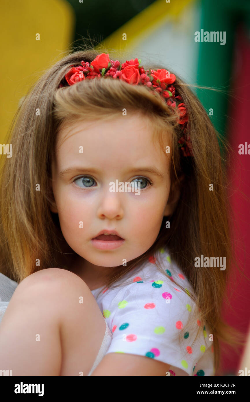 Portrait of the charming girl of 4-5 years. Beautiful long fair hair. A  wreath from red colors on the head. Expressive gray-blue eyes. Bright lips  Stock Photo - Alamy