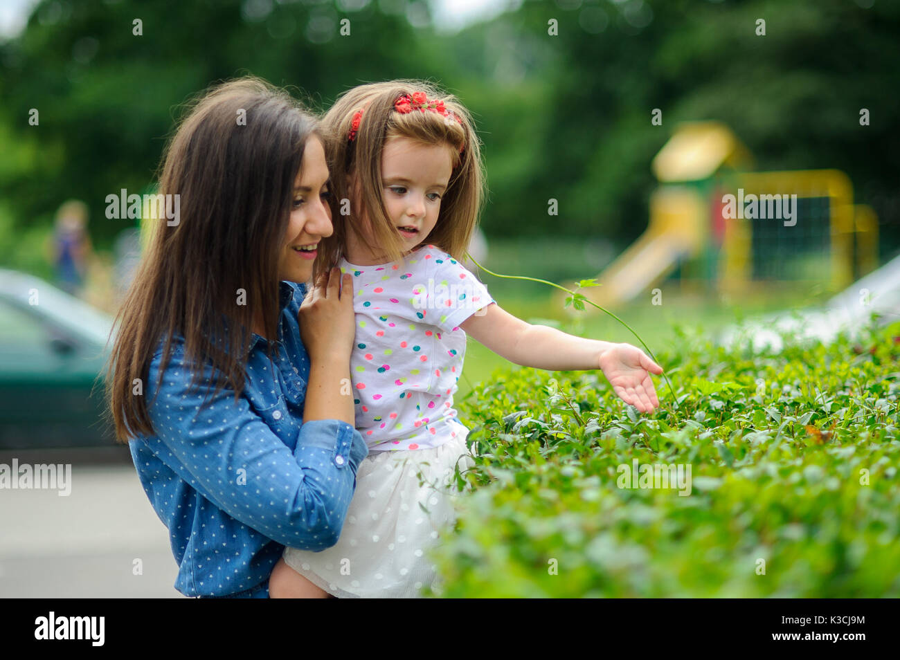 The young woman holds the little daughter on hands. Mother gently ...