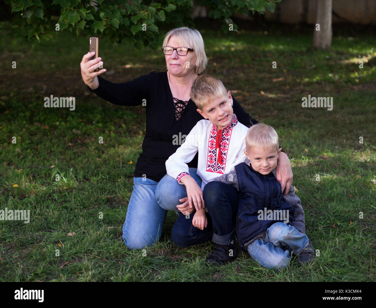 Middle-aged caucasian woman make selfie with her grandsons in the park Stock Photo