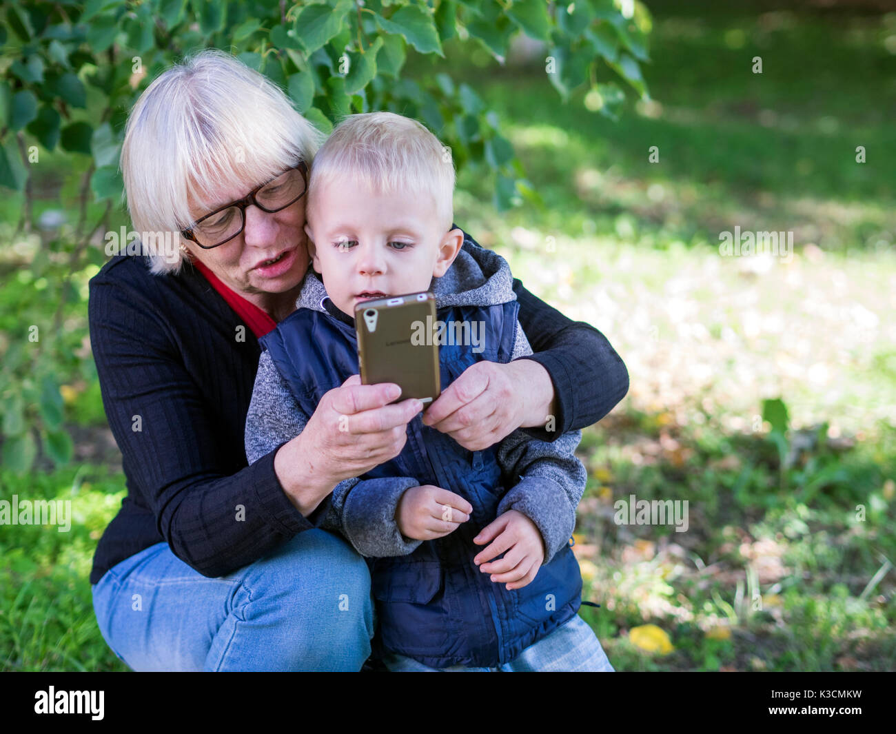 Middle-aged caucasian woman shows selfie with her grandson in the park Stock Photo