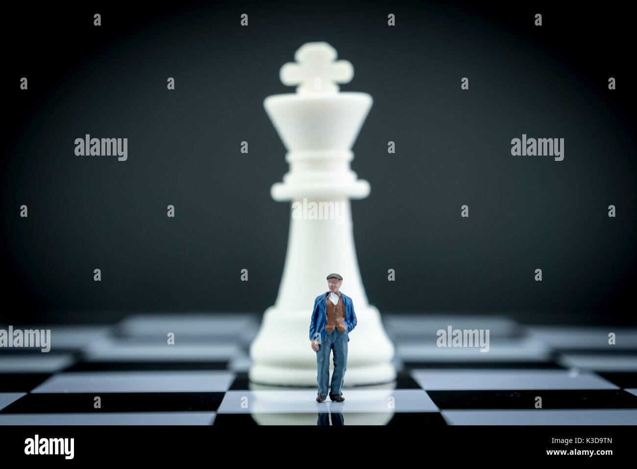 Miniature figure of a man in front of chess piece, conceptual image Stock Photo