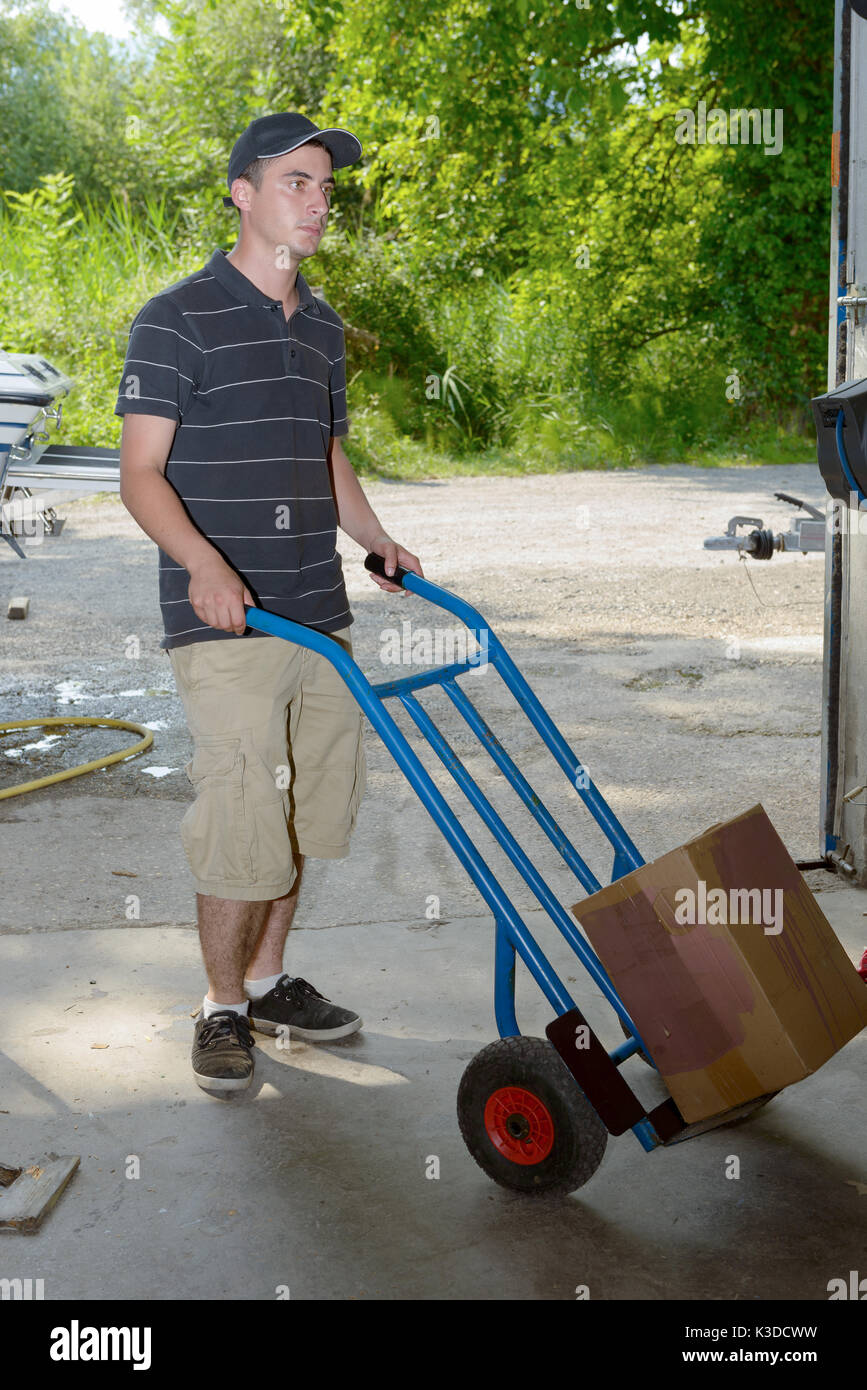 A young employee carries a package  with handtruck Stock Photo